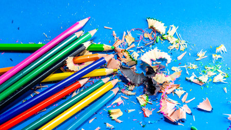 Colored pencils isolated on blue background. Closeup. Sharpened pencil scraps.の写真素材