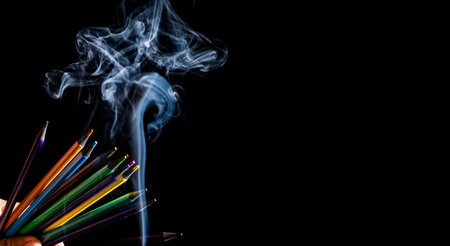 Colored pencils in different directions on black background with white smoke coming from below. Closeup. Sharp pencil scraps.の写真素材