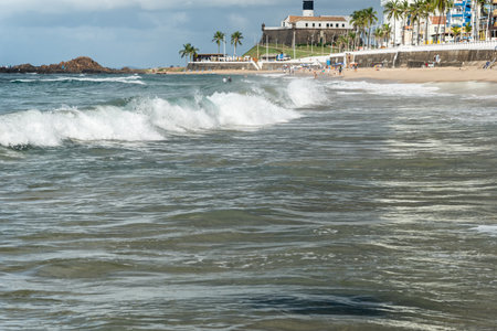Low view of a beach against blue sky and buildings in the background. Barra beach lighthouse,...