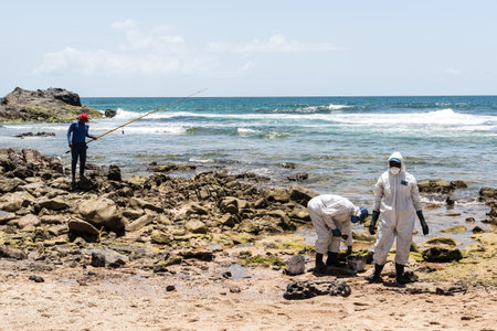 Salvador, Bahia, Brazil - October 26, 2019: Cleaning agents extract oil from Pedra do Sal beach in...