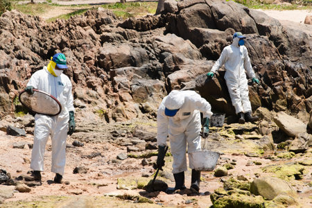 Salvador, Bahia, Brazil - October 26, 2019: Cleaning agents extract oil from Pedra do Sal beach in...
