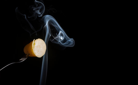 A sweet potato skewered on a fork receiving white smoke from below. Closeup.の写真素材