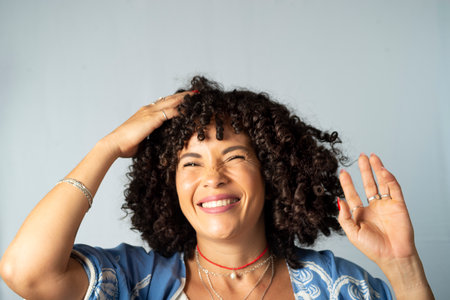 Portrait of smiling beautiful curly hair model against light background. Mature woman. Self esteem concept.の写真素材