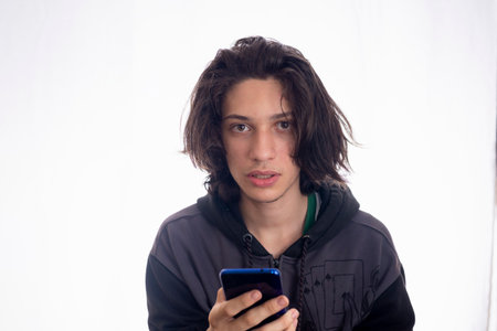 Young man with cellphone in hand against white background. Youth, technology, social and friendship...