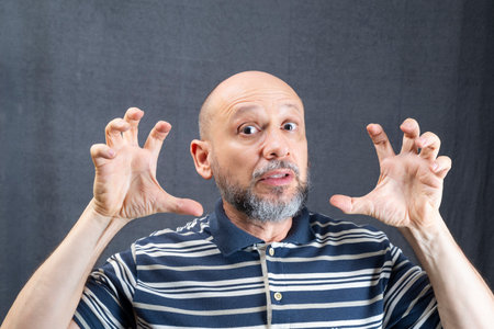 Cheerful funny young bearded business man in classic striped shirt standing making hand gestures....