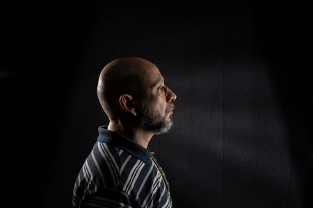 Young handsome bald man with beard wearing casual shirt over black background. Thinking worried....