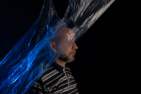 Mature man with a transparent blue plastic bag flying over his head and face. suffocate. face in a...
