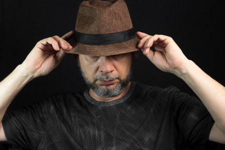 Beardman. With both hands holding the hat. Isolated on black background.の写真素材