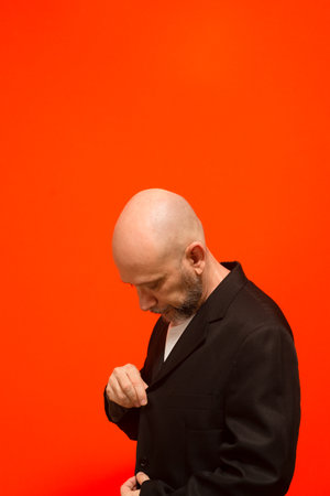 Businessman, successful, elegant, bald and bearded. Isolated on orange background.の写真素材