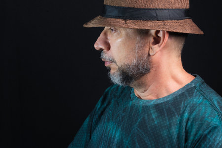 Man wearing hat. Looking to the left side. Isolated on black background.