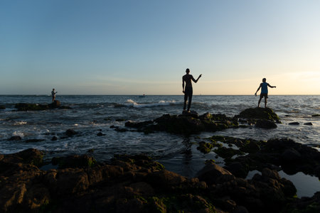 Salvador, Bahia, Brazil - December 11, 2021: Fishermen fishing on top of the rocks at Rio Vermelho beach in Salvador, Bahia.のeditorial素材