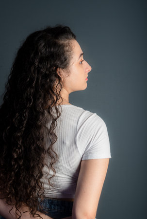 Profile of a beautiful young woman with black hair wearing a white shirt. Against gray background.の写真素材