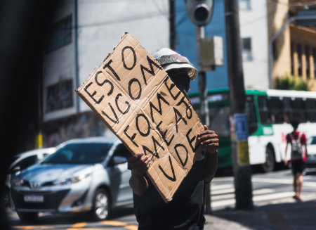 Salvador, Bahia, Brazil - May 06, 2022: Beggar asking for money and food with a sign in traffic in Salvador, Bahia.のeditorial素材