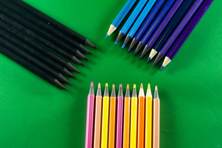 Color pencils on green background. stacked side by side. Close-up.