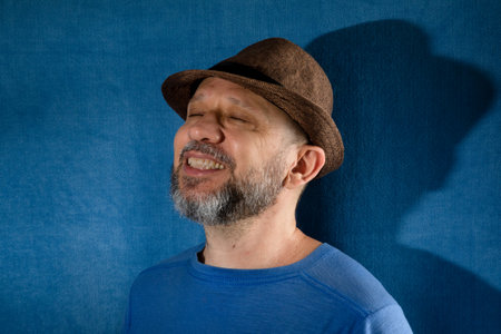 Smiling man wearing hat. Isolated on blue background with shadow.