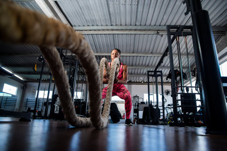 Woman doing training with naval rope. Abdominal strengthening and muscular endurance.