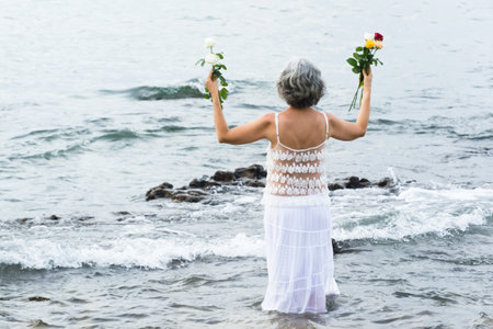 Salvador, Bahia, Brazil - February 02, 2017: A woman who admires Candomble throws flowers into the sea in honor of Iemanja on her feast day. Salvador, Bahia.の写真素材