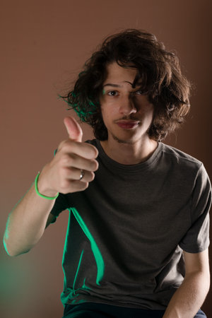 Handsome young man making thumbs up sign. Isolated Bisque background.の写真素材