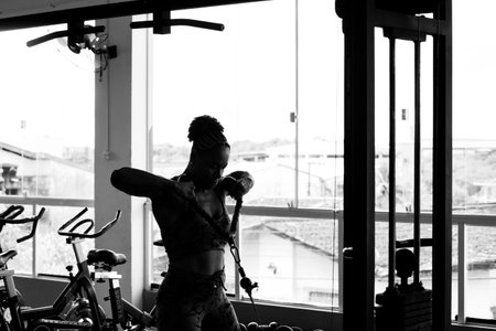 Muscular woman doing exercises for arm and shoulder muscles. Fitness exercise in the studio.の写真素材