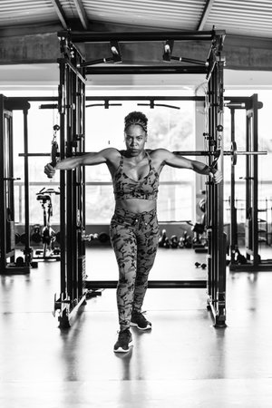 Muscular woman doing arm exercises on a machine at the gym. Determination and focus.