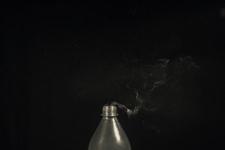 Smoke coming out of a plastic bottle against a black background. design element. Aromatherapy.の写真素材