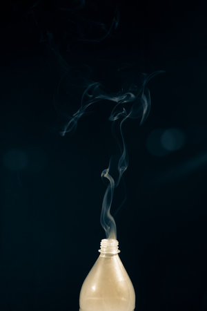 Moving smoke coming out of a plastic bottle. Isolated on black background.の写真素材