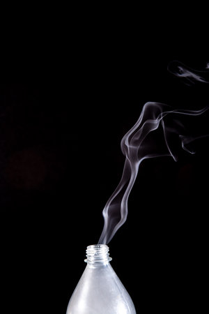 Smoke coming out of a plastic bottle against a black background. design element. Aromatherapy.の写真素材
