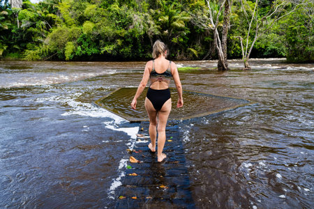 A woman walking on a wooden bridge across the river. City of Valenca, Bahiaの写真素材