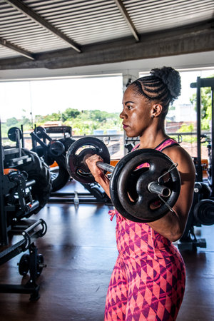 Determined woman lifting weights at the gym. Strengthening the arms.の写真素材
