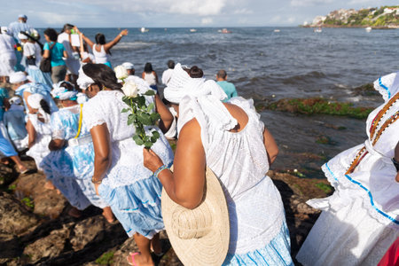 Salvador, Bahia, Brazil - February 02, 2023: Candomble supporters walk on top of the rocks on Rio Vermelho beach to offer gifts to Yemanja, in Salvador, Bahia.のeditorial素材