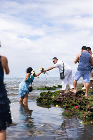 Salvador, Bahia, Brazil - February 02, 2023: Candomble people are in the water on the rocks of Rio Vermelho beach, offering gifts to Yemanja, in Salvador, Bahia.のeditorial素材