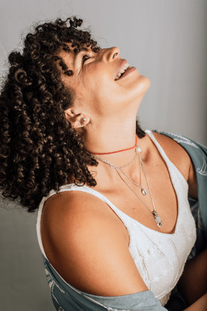 Very smiling and happy woman sitting on a wooden stool. Isolated on gray background.の写真素材