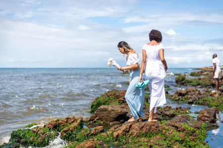 Salvador, Bahia, Brazil - February 02, 2023: Candomble people are on the rocks of Rio Vermelho beach, offering gifts to Yemanja. Salvador, Bahia.のeditorial素材