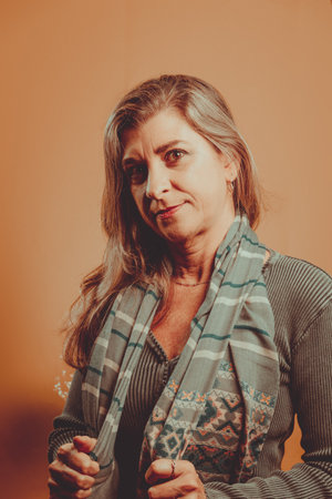 Vertical portrait of beautiful woman wearing colorful scarf. Isolated on brown background.の写真素材