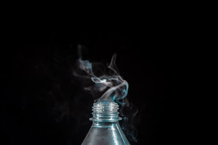 Moving smoke coming out of a plastic bottle. Isolated on black background.の写真素材