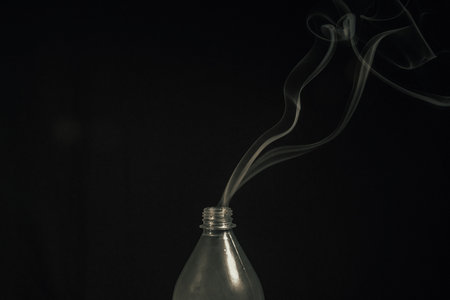Smoke coming out of a plastic bottle against a black background. design element. Aromatherapy.の写真素材