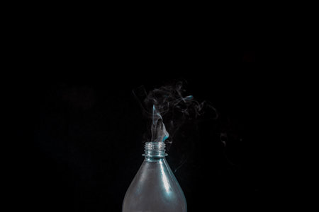 Smoke coming out of a plastic bottle against a black background. design element. Aromatherapy.の写真素材