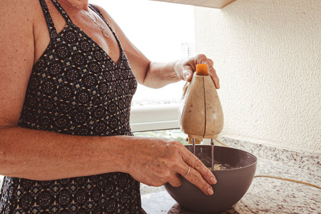Woman using electric mixer for preparing cheesecake ingredients. Family gastronomy.の写真素材