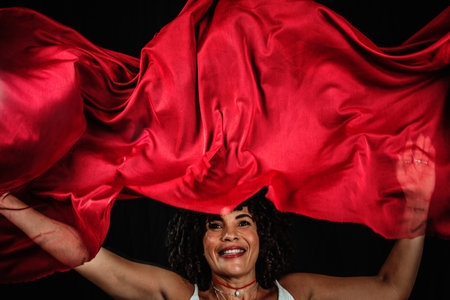 Portrait of a woman manipulating a red cloth. Isolated on black background.の写真素材