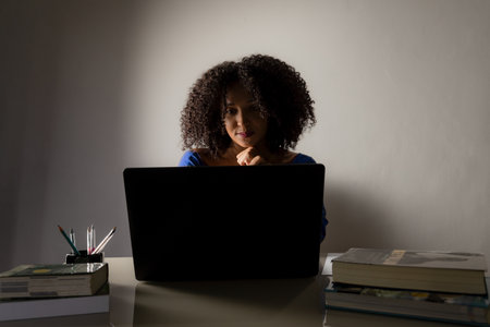 Young pretty businesswoman working late at night with laptop. Home office.の写真素材
