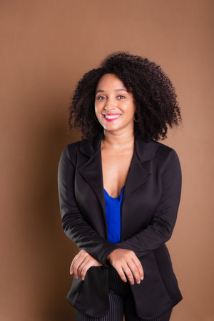 Woman dressed in black blazer standing against brown background. Business woman. studio portrait.の写真素材