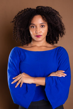 Beautiful young business woman. Wearing blue shirt and confident. Standing against a brown background. studio portrait.の写真素材