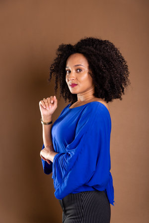 Beautiful young business woman. Wearing blue shirt and confident. Standing against a brown background. studio portrait.の写真素材