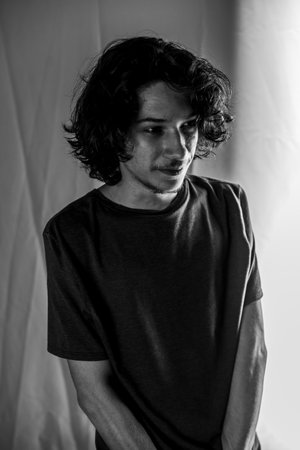 Black and white studio portrait of a beautiful young man. Isolated against Bisque background.