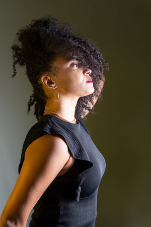 Beautiful young woman in profile wearing black clothing, with hair in her face. studio portrait.の写真素材