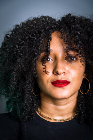 Vertical close-up portrait of a beautiful young woman with hair on her face. studio portrait.の写真素材