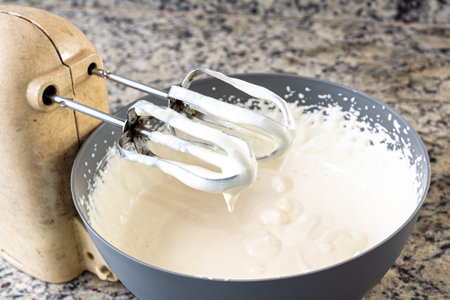 Part of the electric mixer loaded with cream for cheesecake preparation. Family gastronomy.の写真素材