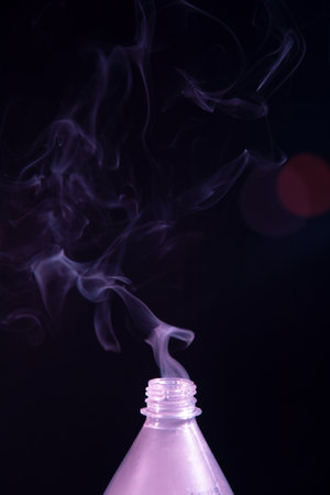 Moving smoke coming out of a plastic bottle. Isolated on black background.の写真素材
