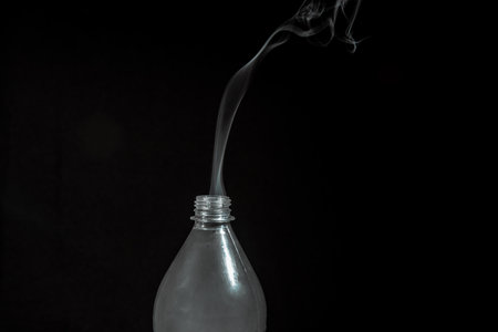 Smoke coming out of a plastic bottle against a black background. design element. Aromatherapy.の写真素材