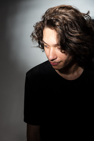 Portrait of young handsome man with long hair isolated on white background with shadows.